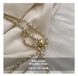 Macro view of adjustable gold chain strap with white leather and metal ball detail