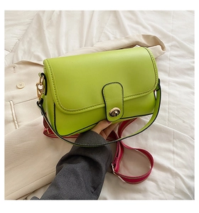 Détail du sac bandoulière en cuir vert lime avec fermoir doré et sangle rayée rouge