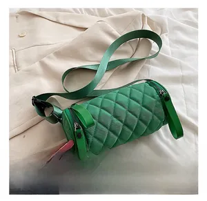 Detail of green quilted cylinder bag featuring dual zippers and wide nylon shoulder strap