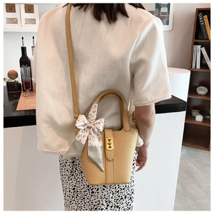 Dettaglio borsa a secchiello in pelle beige con foulard leopardato e oro hardware
