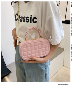 Detail of pink quilted box bag with gold chain strap and twisted woven top handle