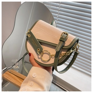 Detail of cream crocodile pattern saddle bag with green trim and gold ring hardware