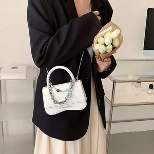 White wave-cut PU leather crossbody bag with chain strap and bead charm on model