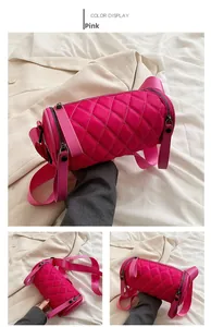 Detail of pink quilted nylon cylinder bag featuring wide textile strap and zip closure