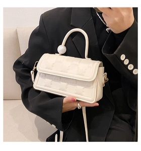 Détail du sac carré ivoire avec texture ours et poignée ornée d'une perle dorée