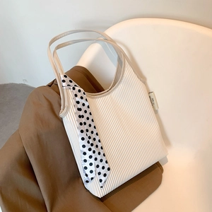 Chic cream pleated shoulder bag with polka dot scarf on a warm aesthetic background