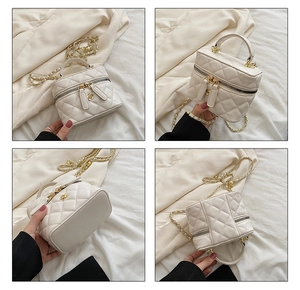 Detail of white quilted mini box bag featuring gold chain strap and floral charm detail