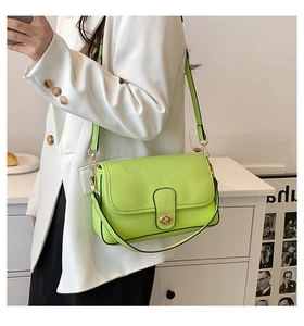 Sac bandoulière vert citron avec fermoir doré porté sur une veste blanche chic