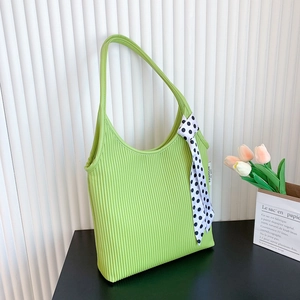 Chic green corduroy shoulder bag with polka dot scarf detail on minimalist background