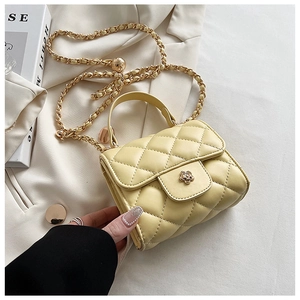 Close-up of yellow quilted mini bag featuring a gold floral clasp and chain strap