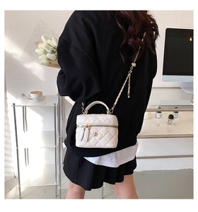 Quilted white mini crossbody bag with gold flower logo shown in a chic studio setting