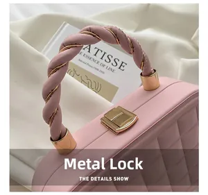Detailed close-up of pink quilted box bag showing golden hardware twist lock and stitching