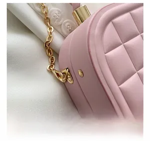Detail of gold metal hook and chain on pink quilted box bag with premium texture
