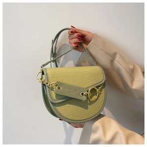 Detail of light green faux crocodile skin texture and gold chain ring on handbag