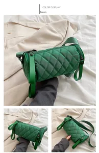 Detail view of a green quilted cylinder bag with wide strap and sleek zipper closure