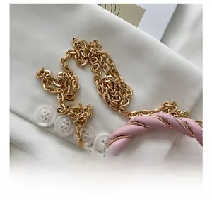Detail of elegant gold metal chain strap and pink leather woven handle of box bag