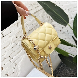 Detail of yellow quilted mini cloud bag featuring gold flower clasp and chain strap