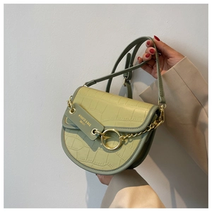 Detail of sage green faux crocodile saddle bag with gold ring and chain accents