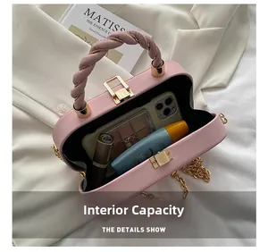 Internal capacity of pink mini leather box bag with makeup items and gold chain strap