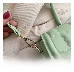 Détails macro des finitions dorées et motifs vagues sur un sac à bandoulière vert menthe