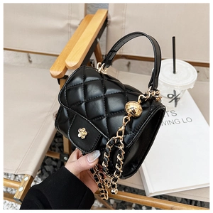 Detail of black quilted leather mini bag with gold camellia clasp and adjustable chain