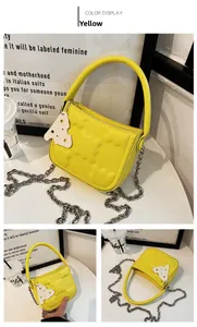 Details der gelben gesteppten Tasche mit Kettenriemen und Käse-Anhänger-Dekoration