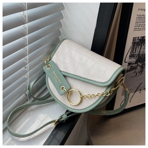 Detail of faux leather saddle bag showing crocodile embossed texture and metal chain