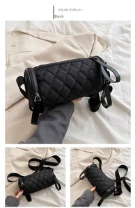 Detail of black quilted nylon cylinder bag featuring wide shoulder strap and metal zipper