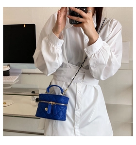 Detail of royal blue quilted vanity bag with gold chain and flower zipper charms