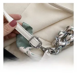 Detail of adjustable shoulder strap with floral silk scarf and silver buckle on bag