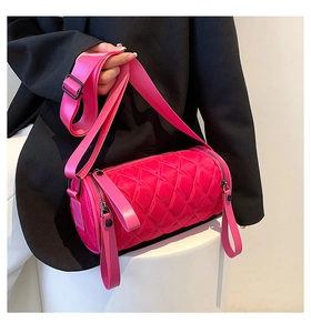 Detail of bright pink quilted cylindrical crossbody bag with wide nylon strap on a model