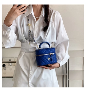 Close-up of blue quilted leather crossbody bag with chain strap on white shirt