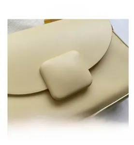 Gros plan du sac en cuir crème avec boucle carrée texturée et coutures de précision