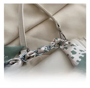 Detail showing silver chain strap with floral scarf wrap on cream leather handbag