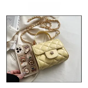 Detail of yellow quilted mini bag featuring golden flower clasp and chain strap