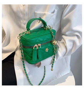 Close-up of bright green quilted mini box bag with gold floral metal clasp and chain