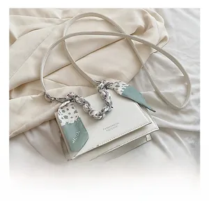 Detailed view of white crossbody bag with floral silk scarf wrapped around the chain handle