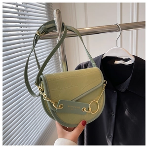 Close-up of light green crocodile pattern saddle bag with gold chain and handle details