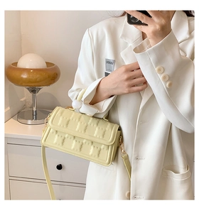 Détail du sac bandoulière matelassé jaune clair avec décor sphérique sur la sangle