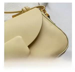 Détail montrant la texture du cuir beige et les finitions dorées du sac à bandoulière