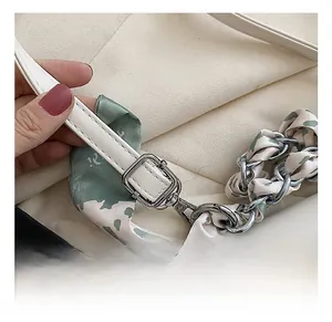 Detailed macro view of white leather shoulder bag with floral silk scarf chain strap