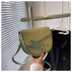 Detail of light green crocodile pattern saddle bag with gold chain and logo plaque