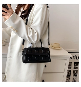 Détail d'un sac bandoulière noir avec motif de vagues et finitions dorées chic