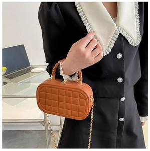 Close-up of brown quilted box bag with dual-tone twisted handle and gold chain strap