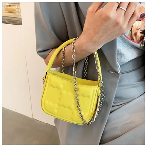 Detail der gelben Mini-Handtasche mit Wellenstruktur und silberner Gliederkette