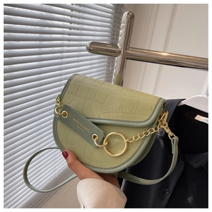 Detail of light green crocodile embossed saddle bag with gold chain and ring buckle