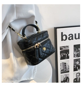Detail of black quilted mini vanity bag with gold chain and camellia charm accessory