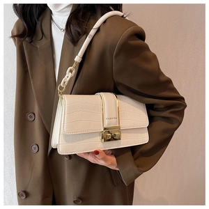 Detailed close-up of cream crocodile pattern leather bag with gold buckle and fashion logo