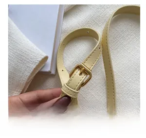 Gros plan de la bandoulière réglable en cuir beige avec boucle en métal doré premium