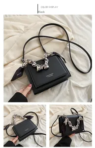 Detail of a black PU leather crossbody bag with decorative leopard silk scarf handle